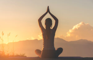 silhouette fitness girl practicing yoga on mountain with sun light